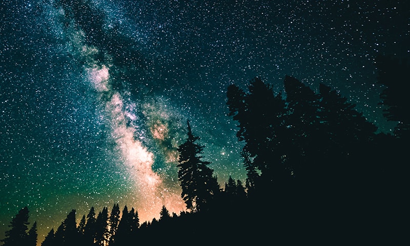 galaxy in night sky with mountain trees in silhouette - sleep hypnosis for insomnia guide