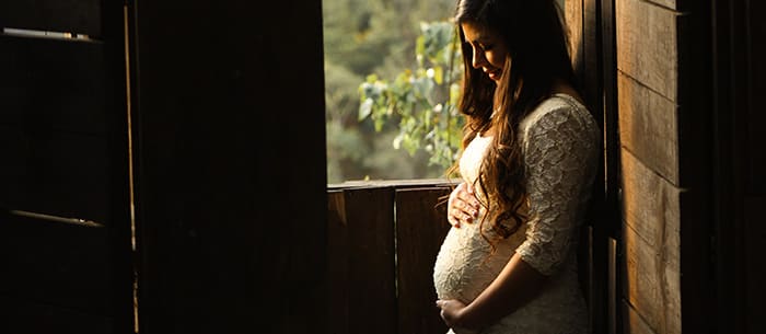 Pregnant woman in white dress holding belly - hypnosis for childbirth guide