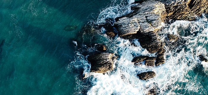 birds eye view of waves crashing into rocks - visual for anxiety hypnosis guide
